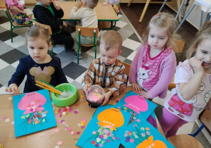 Dzieci przy stolikach robią wazoniki.