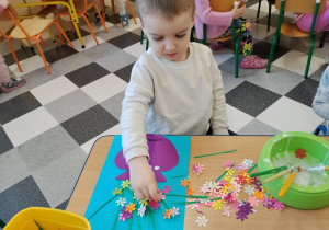 Dzieci przy stolikach robią wazoniki.