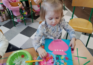 Dzieci przy stolikach robią wazoniki.