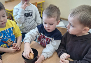 Dzieci sadzą cebulki kwiatów w doniczkach.