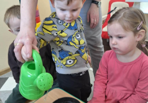 Dzieci sadzą cebulki kwiatów w doniczkach.