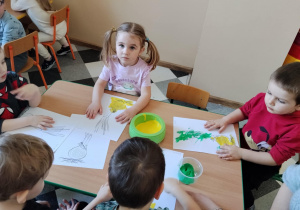 Dzieci malują paluszkami cebulki kwiatów.