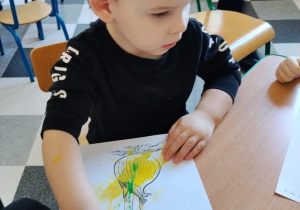 Dzieci malują paluszkami cebulki kwiatów.