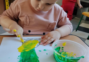 Dzieci malują paluszkami cebulki kwiatów.