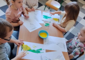 Dzieci malują paluszkami cebulki kwiatów.