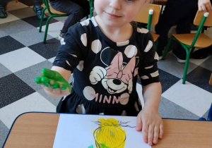 Dzieci malują paluszkami cebulki kwiatów.