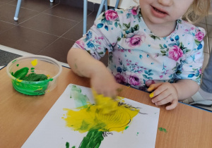 Dzieci malują paluszkami cebulki kwiatów.