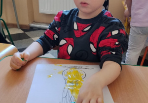 Dzieci malują paluszkami cebulki kwiatów.