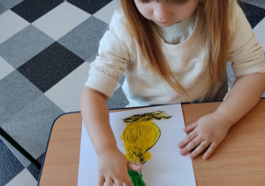 Dzieci malują paluszkami cebulki kwiatów.