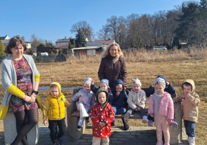 Dzieci nad zalewem siedzą na ławeczce.