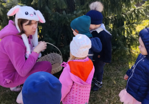 Dzieci wraz z zającem szukają upominków na placu żłobkowym.