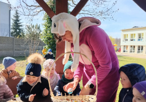 Dzieci wraz z zającem szukają upominków na placu żłobkowym.