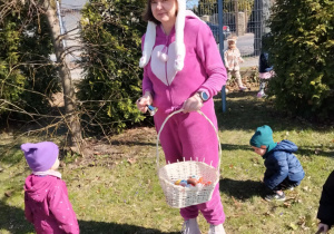 Dzieci wraz z zającem szukają upominków na placu żłobkowym.