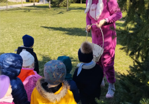 Dzieci wraz z zającem szukają upominków na placu żłobkowym.